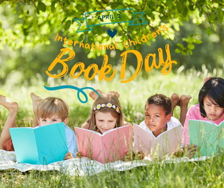 Four children laying in the grass reading books for International Children's Book Day.